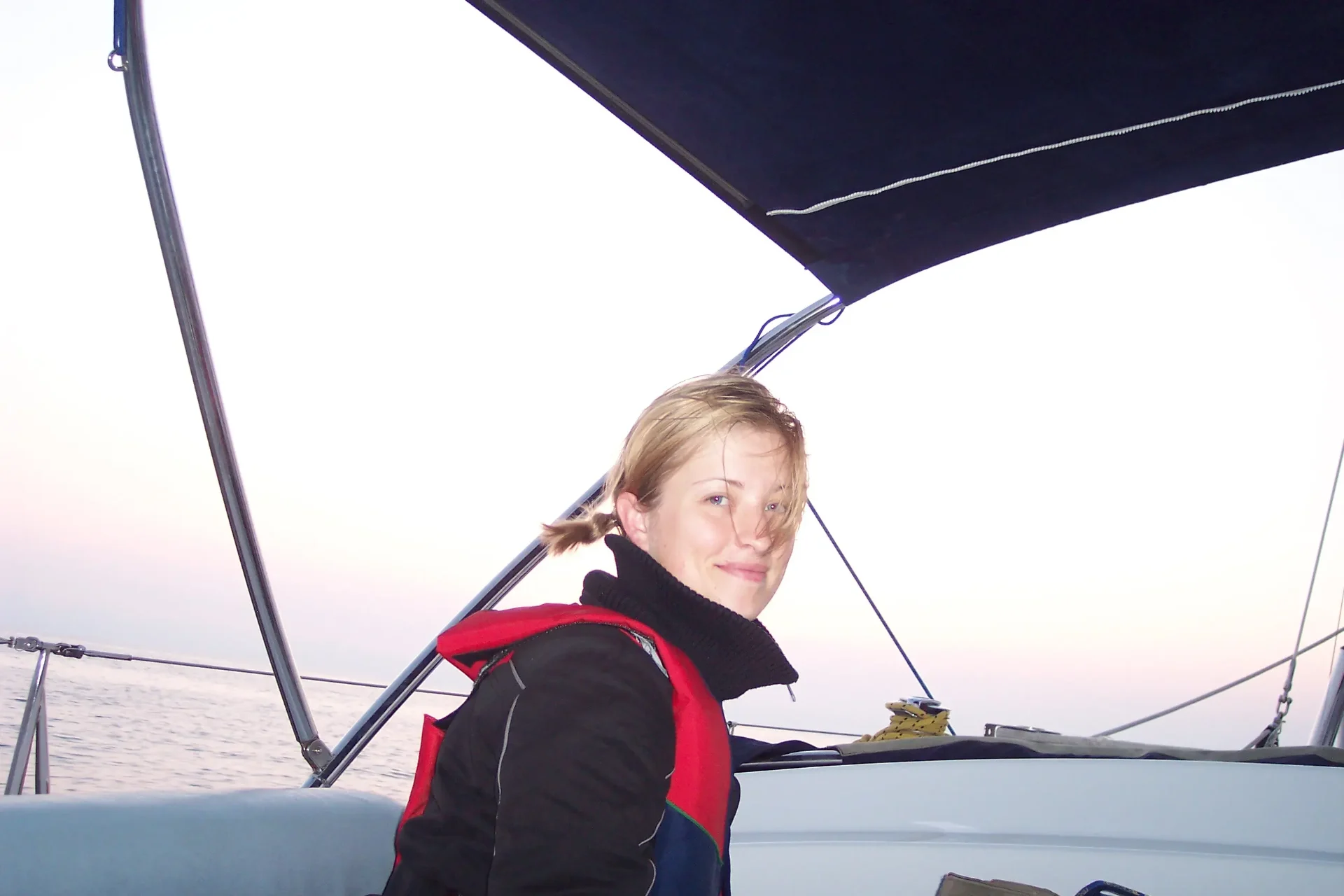 Kristina Agustin sailing at dusk during her early maritime career — open ocean, life jacket, looking back over her shoulder